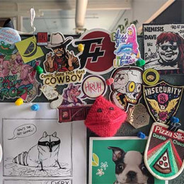 a cubicle wall wiht a bunch of stickers on it, F+ and otherwise