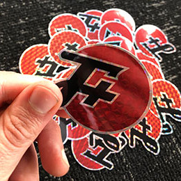 a stack of prismatic F+ stickers, with one in a hand