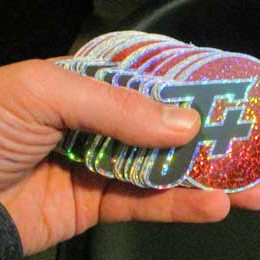a stack of glittery f plus logo stickers in a human hand