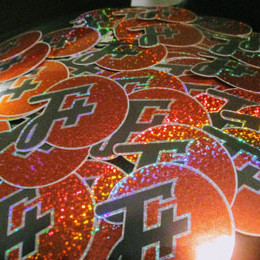 many glittery f plus logo stickers on a stool